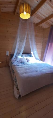 ein Schlafzimmer mit einem Bett in einem Holzzimmer in der Unterkunft Chalet 1 chambre 2-4 personnes in Villainville