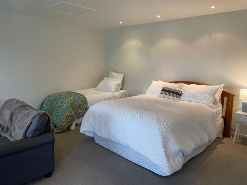 a bedroom with two beds and a couch at Cosy Cottage in the Vines in Waipara