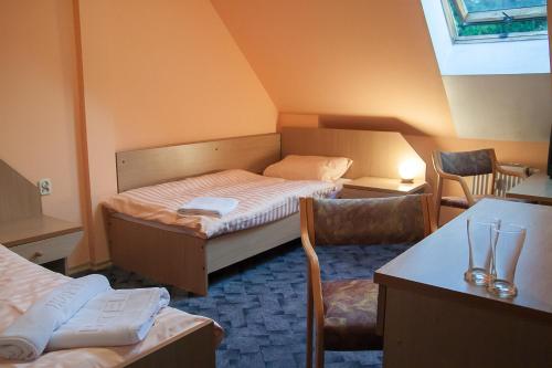 a small room with a bed and a table and chairs at Hotel Aeroplan in Zielona Góra
