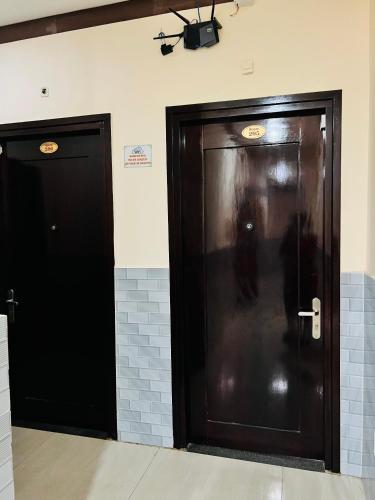 two dark wooden doors in a room with tiles at Mekong Rose Hotel in Can Tho