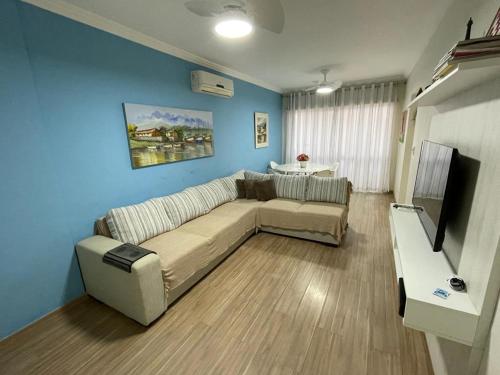 uma sala de estar com um sofá e uma televisão em Apartamento Confortável Guarujá no Guarujá