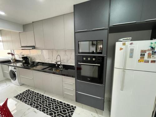 kuchnia z czarnymi urządzeniami i białą lodówką w obiekcie Apartamento Confortável Guarujá w mieście Guarujá