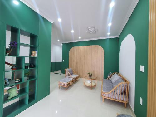 a living room with green walls and two chairs at SÂM LÂM HOUSE - Bảo Lộc in Bao Loc