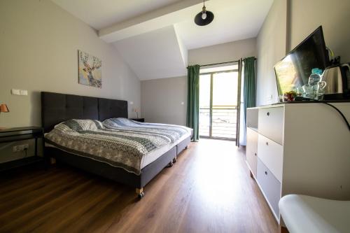 a bedroom with a bed and a dresser and a window at Róża Wiatrów in Węgorzewo