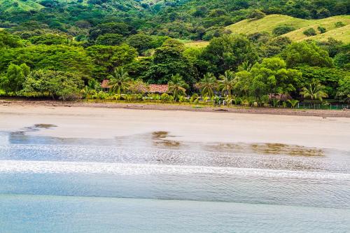 a beach with trees and mountains in the background at Villa Marina Lodge & Condos in Playa Venao