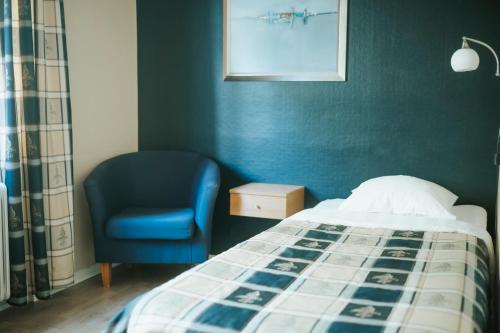 um quarto com uma cama e uma cadeira azul em Nadden Hotell & Konferens em Ramnäs