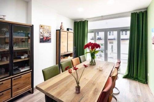 une salle à manger avec une table en bois et des fleurs. dans l'établissement Edelweis, à Blankenberge