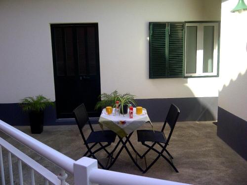 uma mesa com cadeiras e bebidas numa varanda em Holidays Madeira em São Vicente