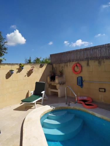 a swimming pool with a chair next to a building at Gozo Rustic Farmhouse with stunning views and swimming pool in Sannat