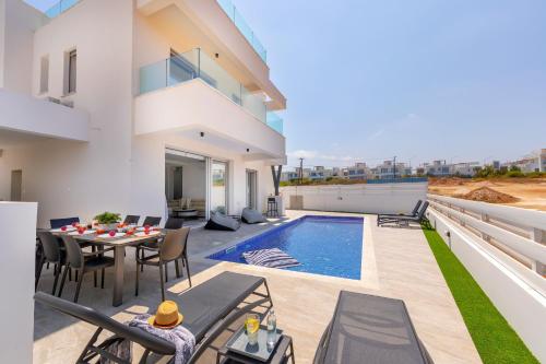 a patio with a table and chairs and a swimming pool at Protaras Sol e Mar Villa 3 in Protaras