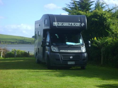 a truck parked in the grass next to a lake at Catlins Newhaven Holiday Park in Owaka