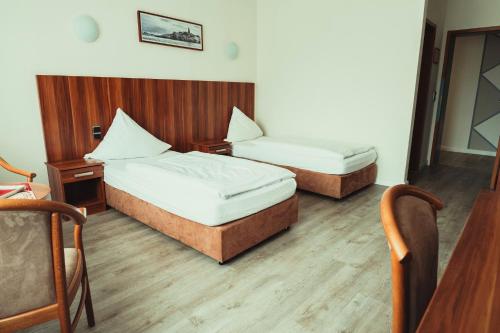 two beds in a room with wooden floors at Schlosspark-Hotel Hof von Oldenburg in Rastede
