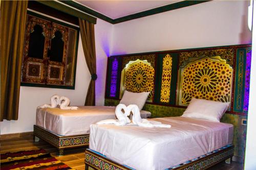 sypialnia z 2 łóżkami z białą pościelą w obiekcie Riad Azemmat w mieście Szafszawan
