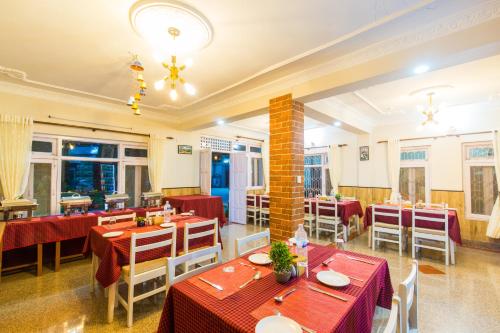 un restaurante con mesas y sillas rojas y ventanas en Hotel Acme Inn en Katmandú