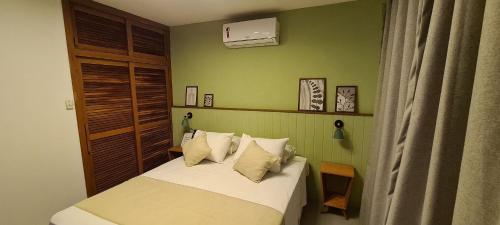 a small bedroom with a bed with white sheets and pillows at Brisas do Amor Apto 109 in Pipa