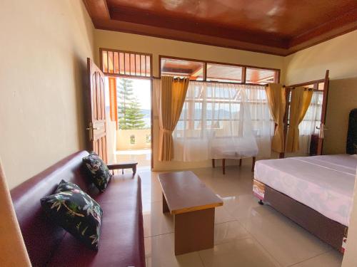a bedroom with a bed and a couch and a window at Lekjon Cottage in Tuktuk Siadong