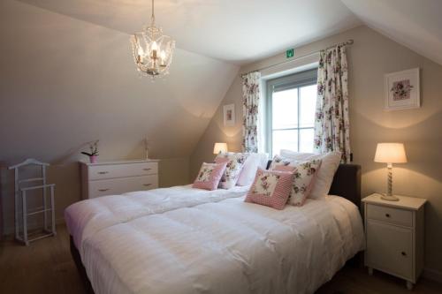 Un dormitorio con una cama blanca con almohadas y una ventana en Cottage d'Hoge Schure, en Heuvelland