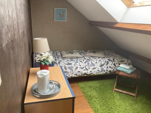 a small room with a bed and a table with a cup on it at Le Papillon d'Or in Arlon