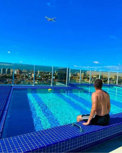 a man sitting in front of a swimming pool at Terraço Harmony Flats GRU in Guarulhos