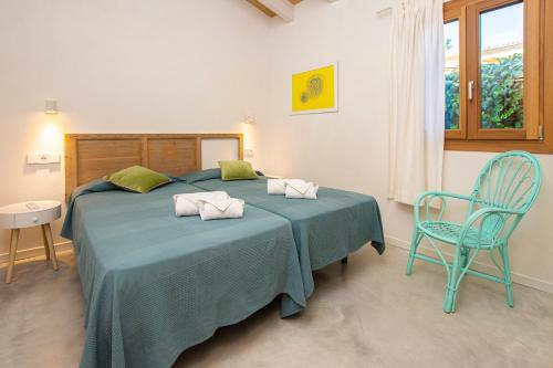 a bedroom with a bed with a blue blanket and a chair at Villa with pool near the beach in Cala San Vicente by Renthousing in Cala de Sant Vicent