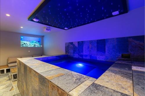 une baignoire jacuzzi dans une pièce avec éclairage violet dans l'établissement Villa gorille - 240m2- 6chb - SPA-Sauna-Babyfoot-Arcade, à Ittenheim