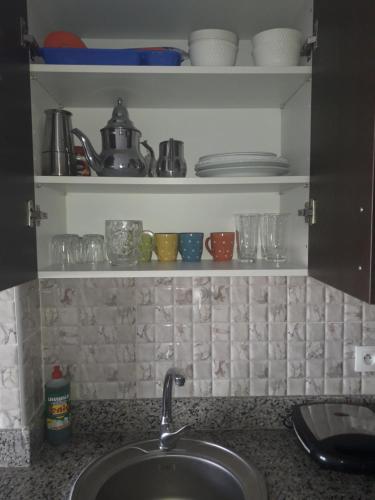 - un comptoir de cuisine avec évier et quelques tasses et assiettes dans l'établissement Charmant Studio piscine mdiq CaboNégro Martil, à Cabo Negro