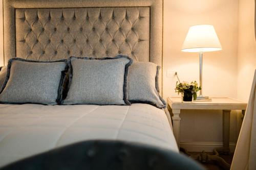 a bed with two pillows and a table with a lamp at CORTE SAGGIN Charme Relais in San Pietro in Cariano