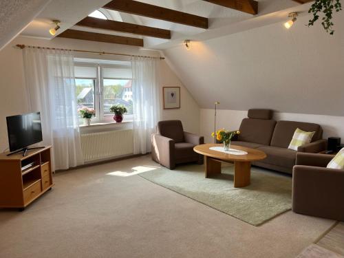 ein Wohnzimmer mit einem Sofa, einem TV und einem Tisch in der Unterkunft Lieblingsort Buxtehude in Buxtehude