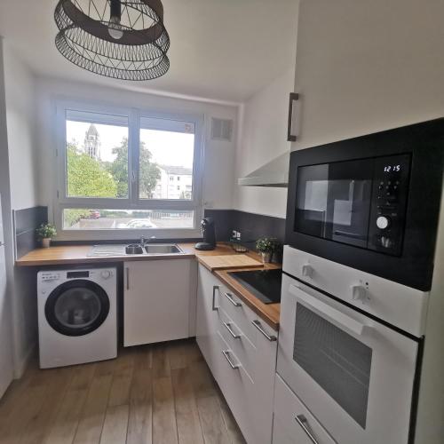 a kitchen with a washer and dryer and a microwave at Chambre Evasion Tout confort Saint Marceau in Orléans