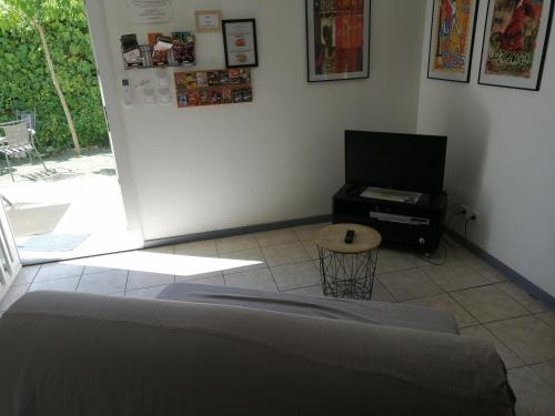 a room with a bed and a tv and a table at Petite maison et son jardinet en Village. in Puisserguier