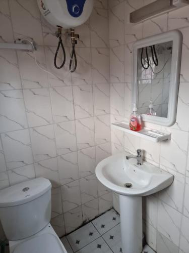 a white bathroom with a toilet and a sink at Baobab Lodge Douala (Bonamoussadi) in Douala
