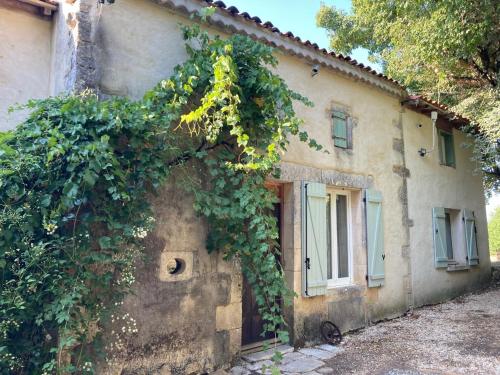 una vieja casa con vides creciendo a su lado en Rustic cottage with stunning swimming pool en Saint-Front