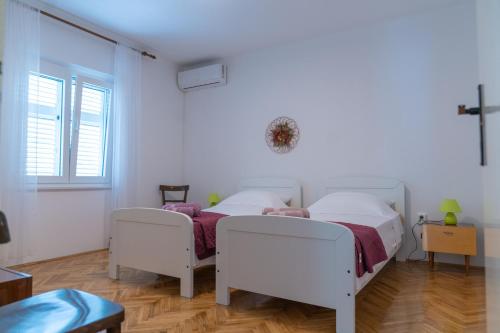 two beds in a room with a cross on the wall at Sidus Maris, Spacious Seaside Apartment with Free Parking in Martinšćica