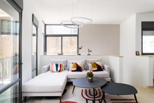 una sala de estar con 2 sofás blancos y una mesa. en Elegant Duplex with XL Patio by FeelHome en Tel Aviv