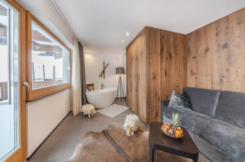 a living room with a couch and a bath tub at Hotel Hell in Ortisei