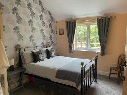 a bedroom with a bed and a window at Walnut Tree Cottage Barn in Toppesfield