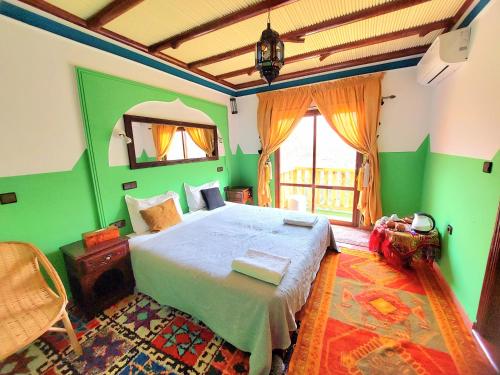 a bedroom with a bed with green walls and a window at Atlas Prestige in Imlil