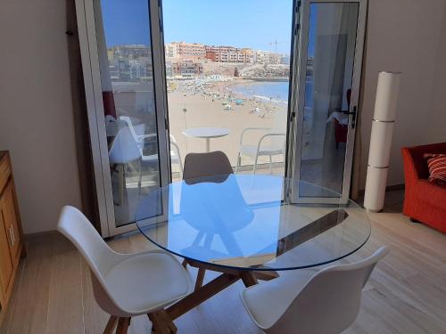a glass table and chairs with a view of a beach at Vistas Melenara by CanariApartment - Beachfront Apartments with Balcony and Fast WiFi in Telde