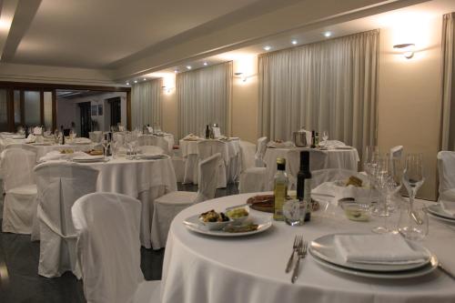 un comedor con mesas blancas y sillas blancas en HOTEL SOLARIS, en Casalbordino