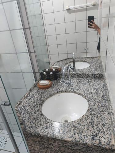 a bathroom counter with two sinks and a person taking a picture at Pousada Samba do Kite in Jericoacoara
