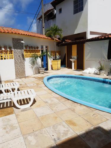 a swimming pool with two lounge chairs next to a house at Suítes São Francisco in Porto De Galinhas