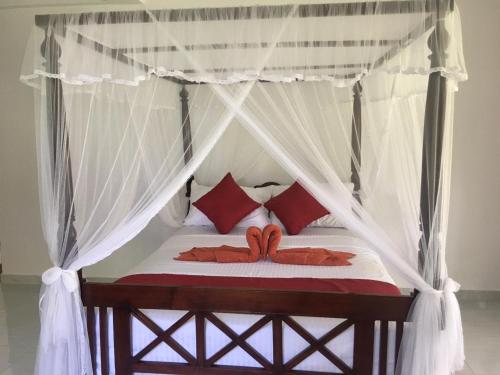 ein Schlafzimmer mit einem Himmelbett und roten Kissen in der Unterkunft Lush Green Villa in Talpe