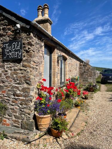 a stone building with flowers in front of it at The Old Pottery, Unique Views & Spa-like Bathroom in Ashburton