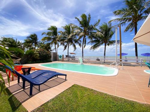 uma piscina com uma cadeira e palmeiras e o oceano em Mon Chéri - Pousada Exclusive em Japaratinga
