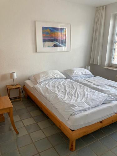 a large bed in a bedroom with a picture on the wall at Haus Karin Wohnung 1 in Wittdün