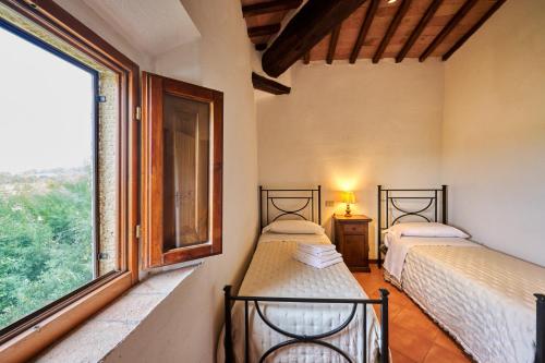 two beds in a room with a large window at Agriturismo il Canneto in Casole dʼElsa