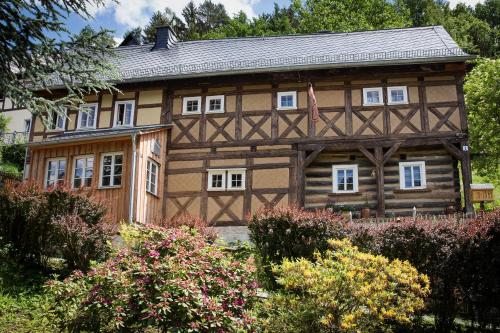 ein großes Holzhaus mit weißen Fenstern in der Unterkunft Kulturdenkmal Umgebinde1657 in Bad Schandau