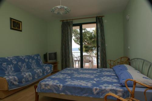 um quarto com uma cama, um sofá e uma janela em Apartments by the sea Marusici, Omis - 2741 em Mimice
