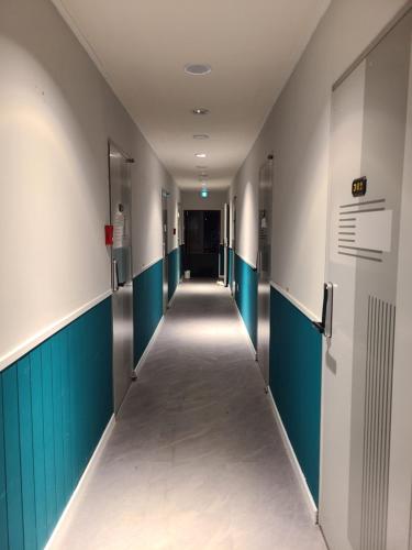 a corridor of an empty hallway with blue and white walls at Well Plus Guest House in Seoul