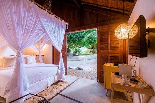 een slaapkamer met een bed, een bureau en een raam bij La Cozinha Bungalow in Barra Grande